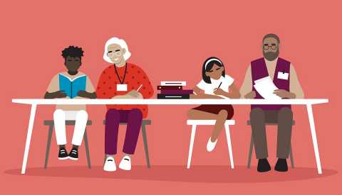 Older adults sitting with students on white table with a stack of books showing them how to read