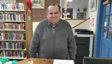 John Bolton Property Tax-Aide Volunteer wearing gray sweatshirt in his home