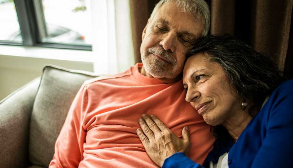 woman sitting next to a man with her head on his shoulder and hand on his chest