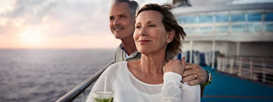Closeup of a middle-aged couple on the deck of a cruise ship looking at the ocean