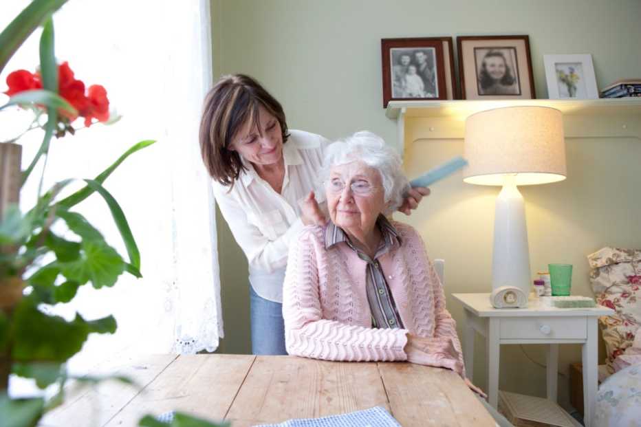 Woman combing hair of elderly mother