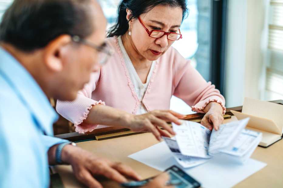 Senior Taiwanese asian couple calculating finance bills at home.