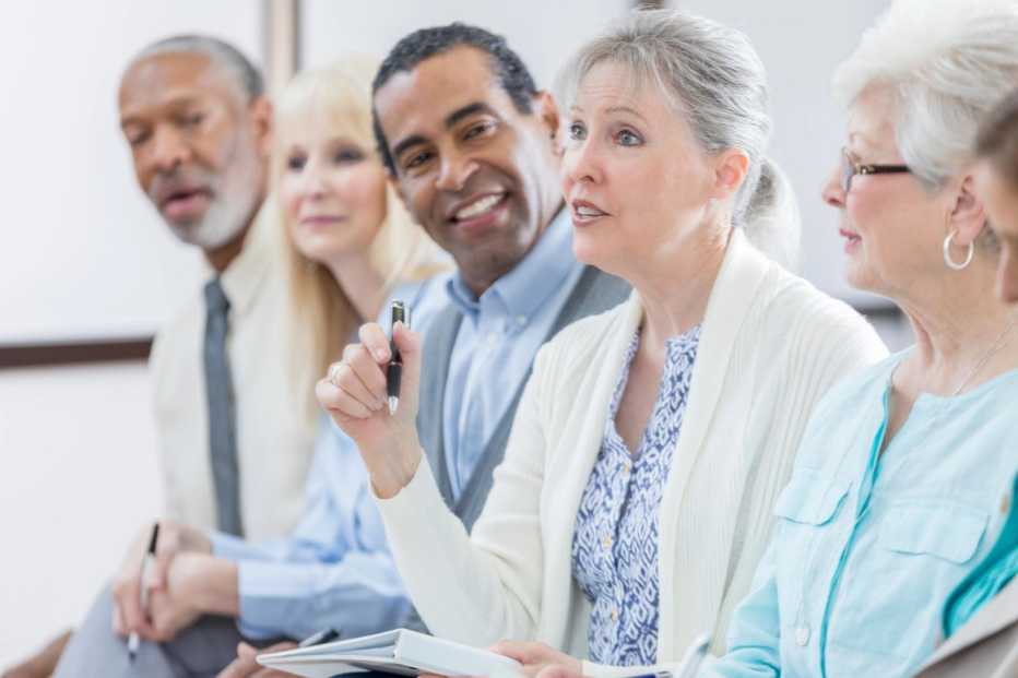 Confident senior woman asks question during seminar