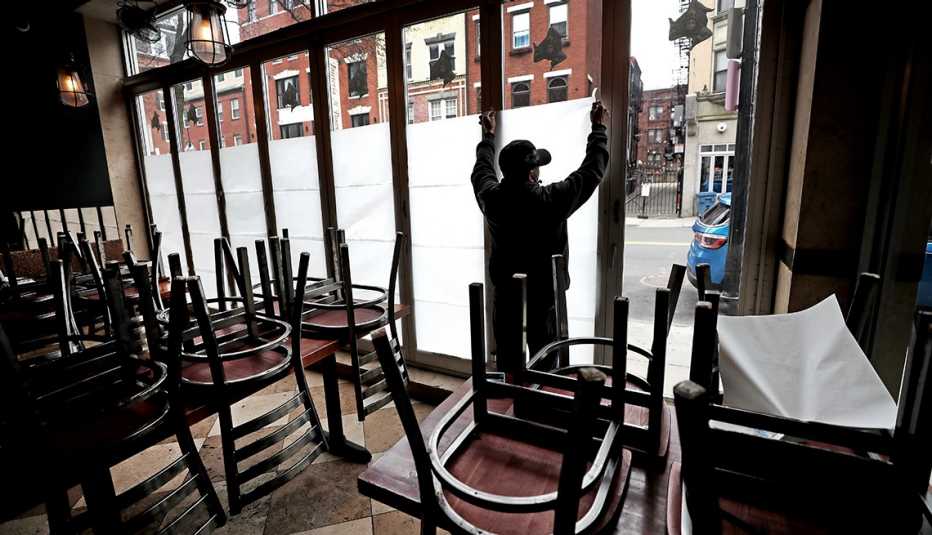 A worker is putting paper over windows of a closed store