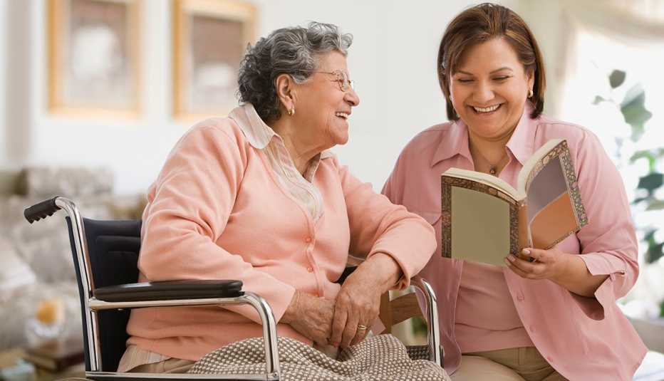 A woman reading to her mother who is sitting in a wheel chair