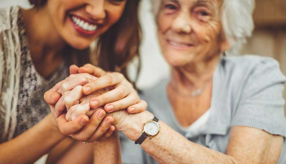 a young woman and an older woman holding hands and smiling