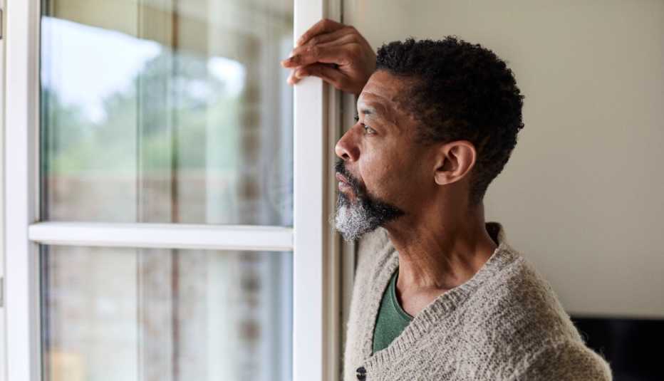 man looks pensively out a window