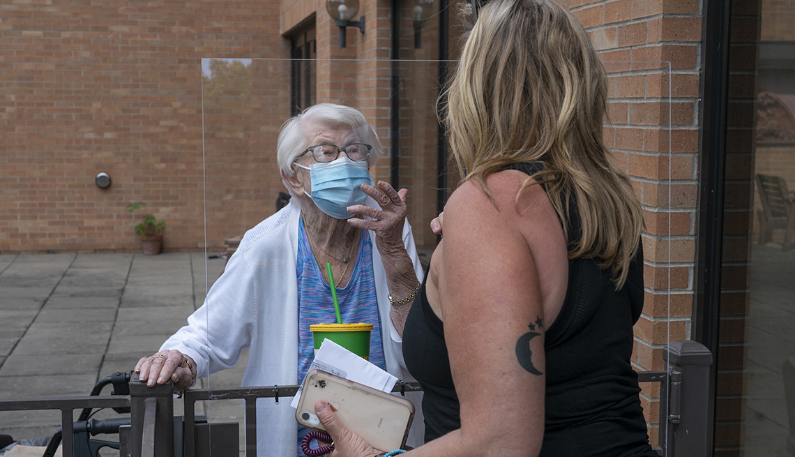 Two women talk to each other with a protective barrier between them