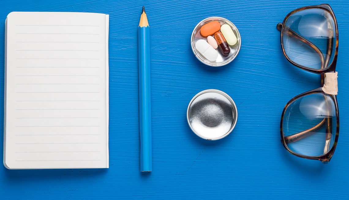 A note pad with blank lined paper,a pen, pillbox and horn rimmed glasses