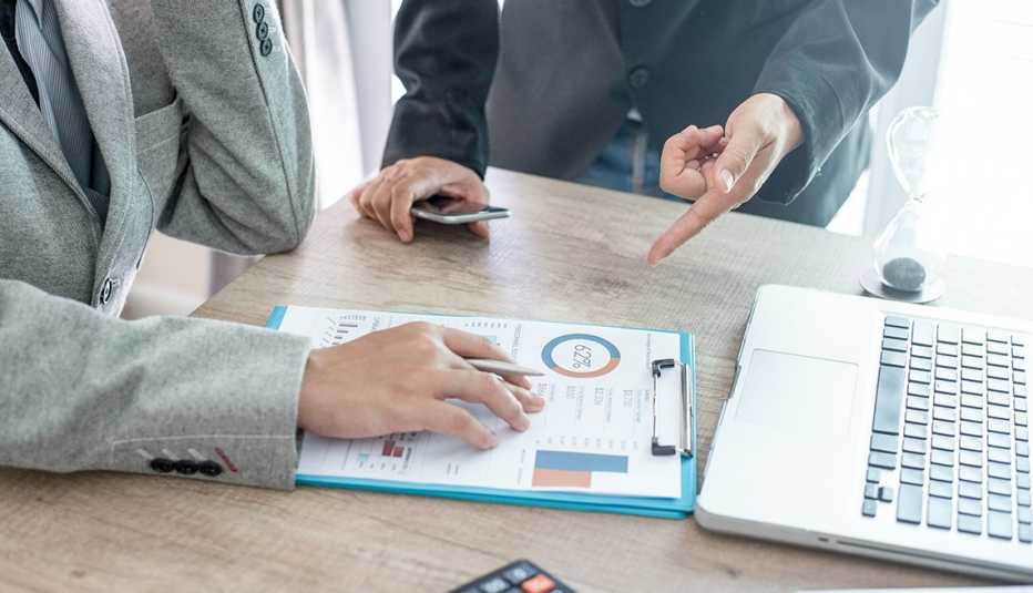 two people looking at financial documents, and one pointing at the document