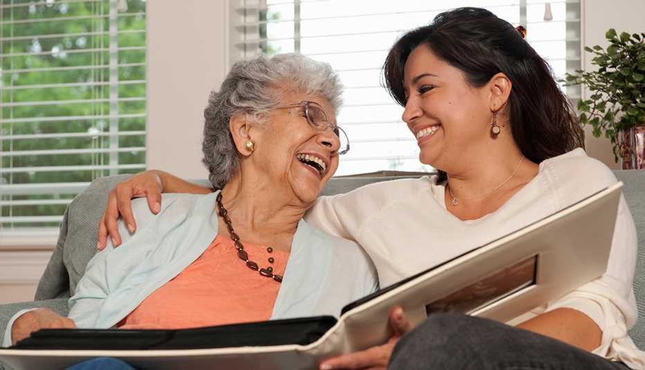 Two women sitting on a couch looking at a photo album