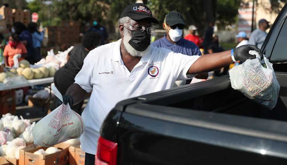 A volunteer places food in the back of a black truck