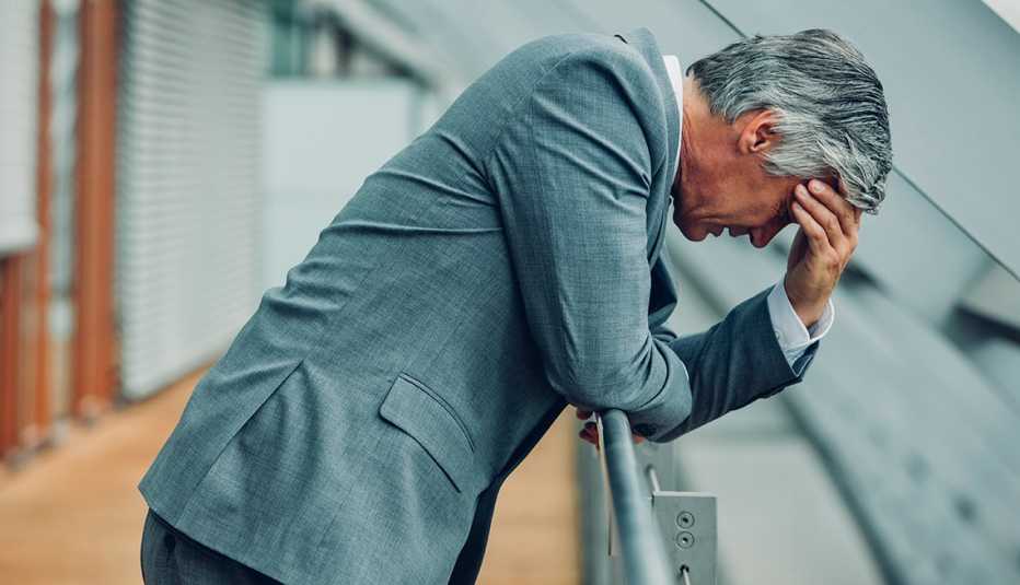 An older man looks depressed with his head in his hands