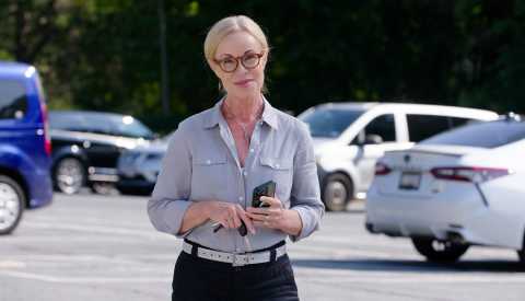 a woman is standing in a parking lot with her phone