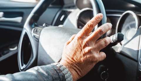 a man's hand rests on a steering wheel a man's hand rests on a steering wheel