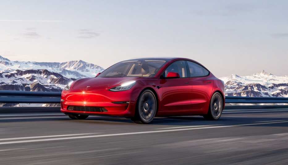 a tesla model three driving through the mountains