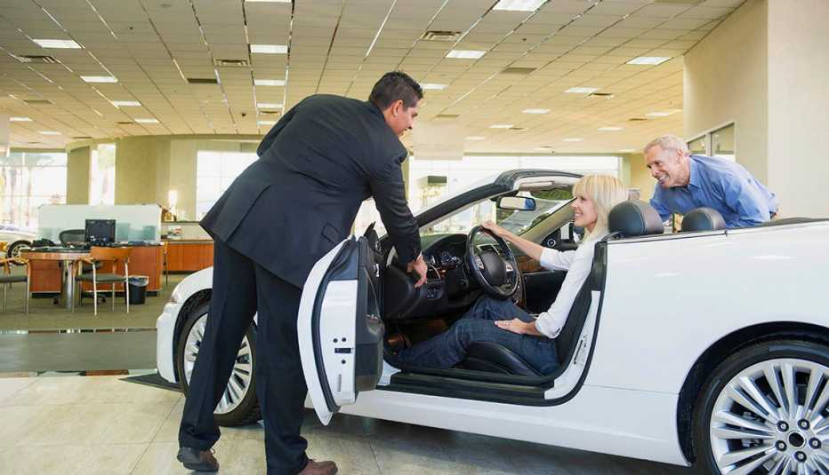 couple sitting in a convertible at car dealership