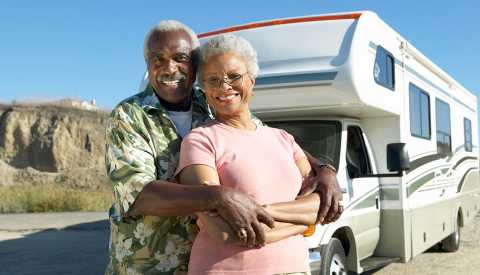 a happy couple standing in front of their r v a happy couple standing in front of their r v