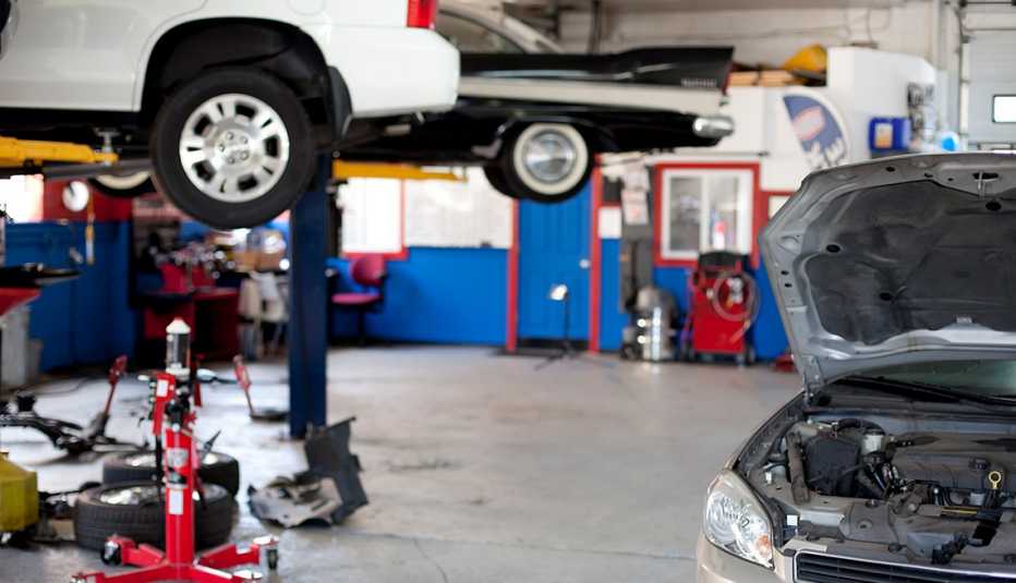 car on lift, another car on the right with hood open in garage