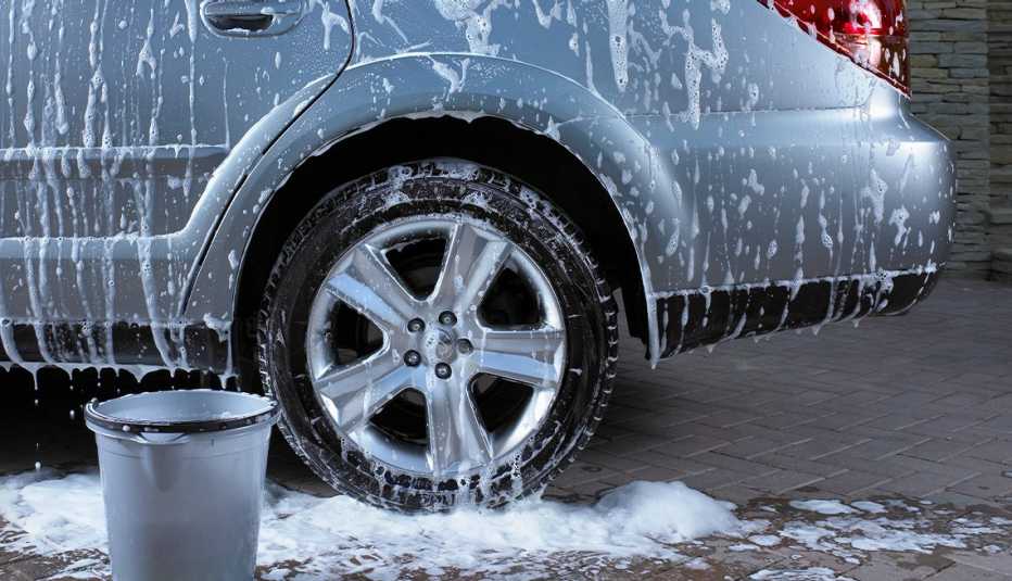 lower drivers side of car with soapy suds on it, bucket next to it