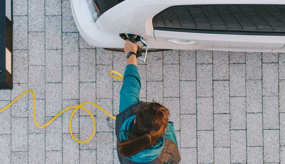 person holding charging hose in charging port of vehicle