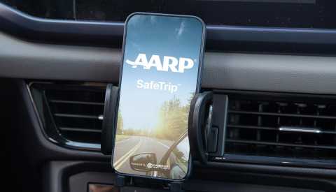 a mobile phone showing aarp safetrip a mobile phone displaying aarp safetrip on a dashboard