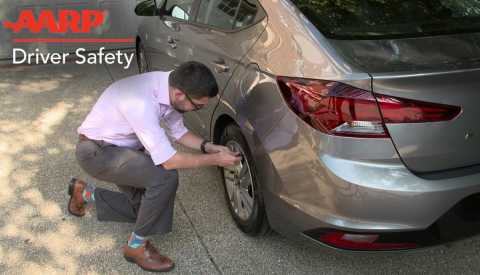 a man in a pink suit puts air in a tire on a gray car a man in a pink suit puts air in a tire on a gray car
