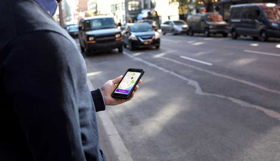 a man checks on his ride hailing app for his vehicles arrival