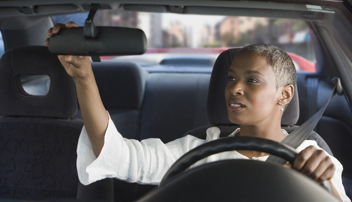 woman adjusting rear view mirror