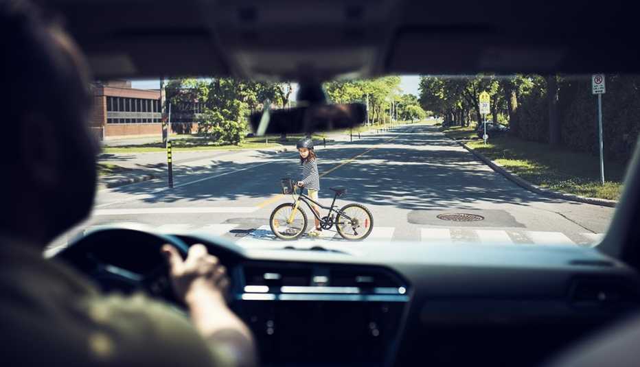 a driver brakes at a crosswalk where I child is walking her bicycle across the street