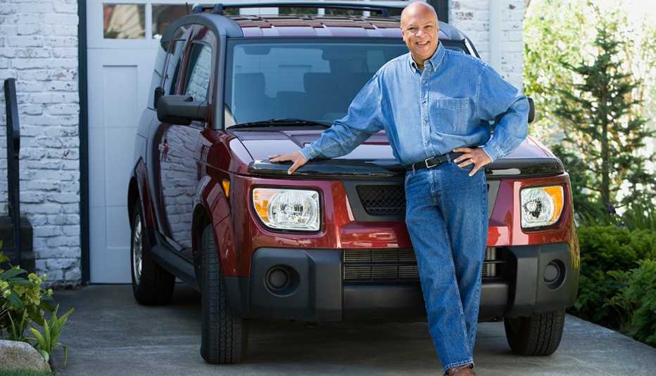 A man stands in front of his red car
