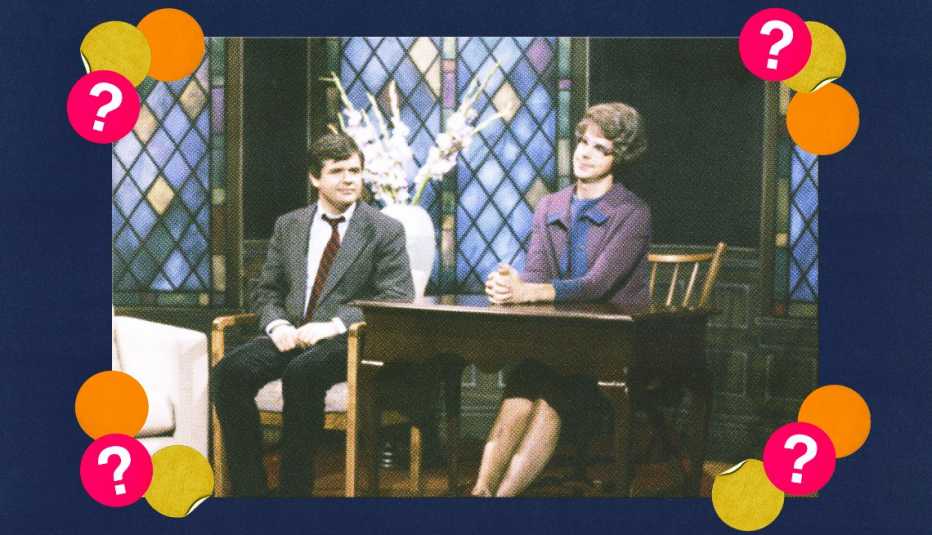 Christopher Durang sitting in chair next to Dana Carvey sitting at table during a skit; surrounded by yellow, orange and red circles with question marks in them