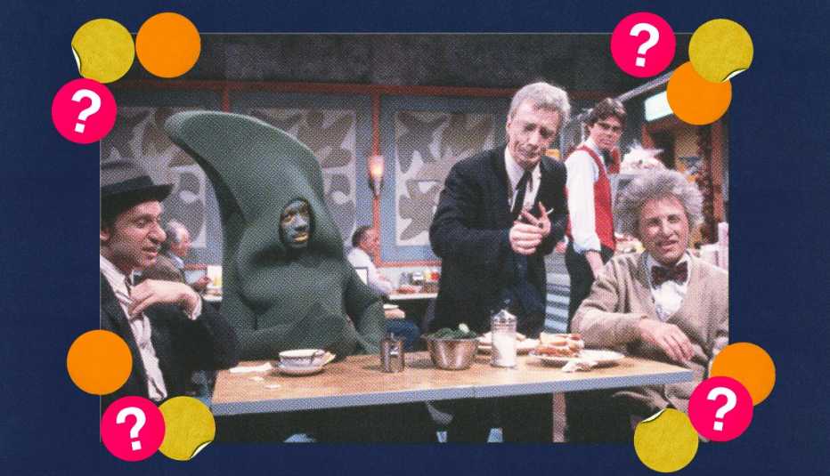 Eddie Murphy in costume in a sketch with other actors; surrounded by yellow, orange and red circles with question marks in them