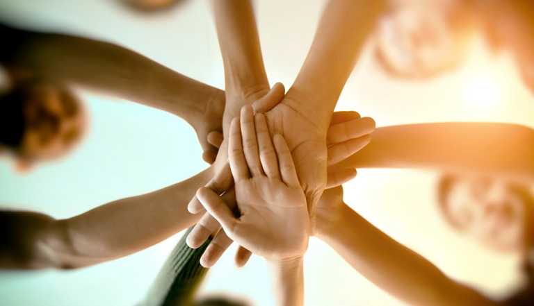 A close-up view of hands from multiple people stacked on top of one another