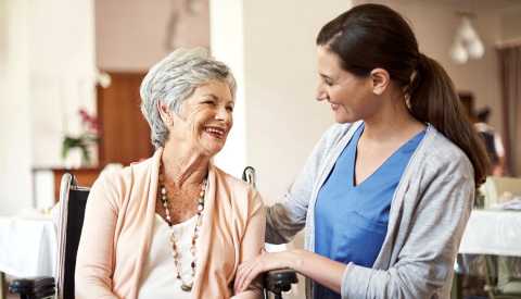 A female nurse helping a senior woman in a caregiving capacity