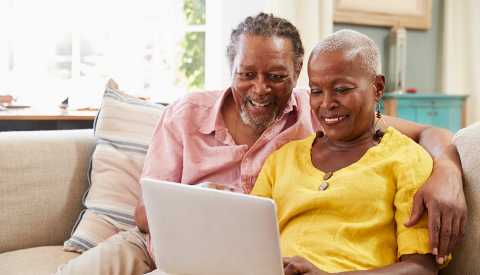 A couple sitting on a sofa at home and using a laptop