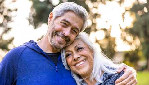 A man and woman couple smiling and side hugging outside