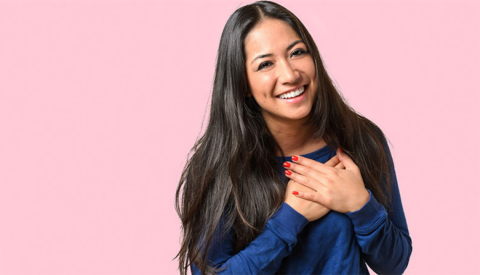 A woman with both hands on her chest over her heart