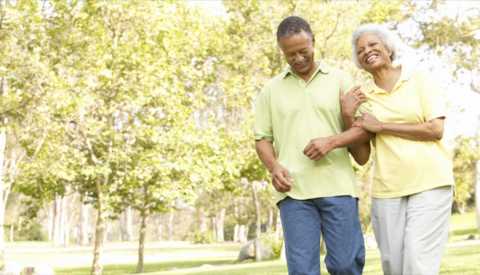 A man and woman couple smiling and walking together in nature