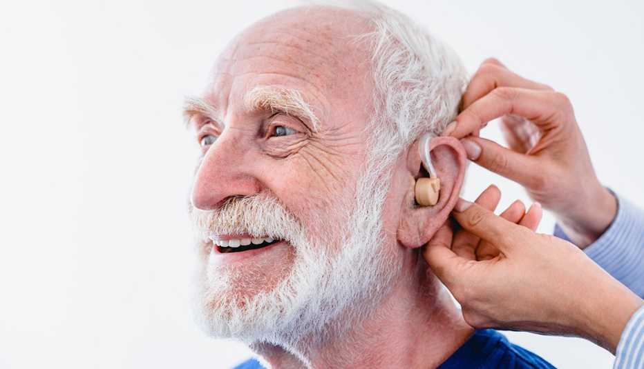A man getting hearing aids installed by another person on a white background