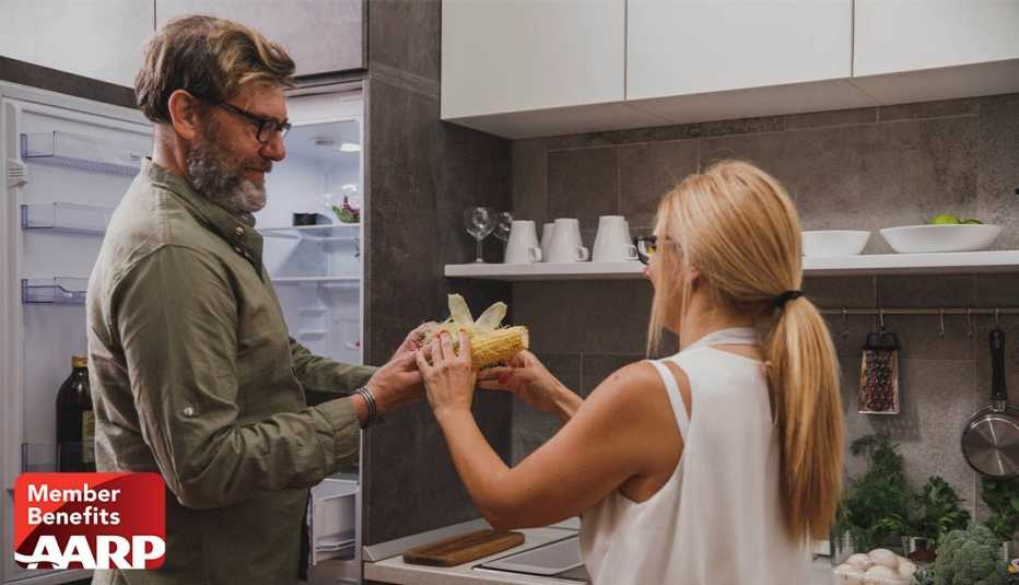 A couple in kitchen sharing a fresh corn