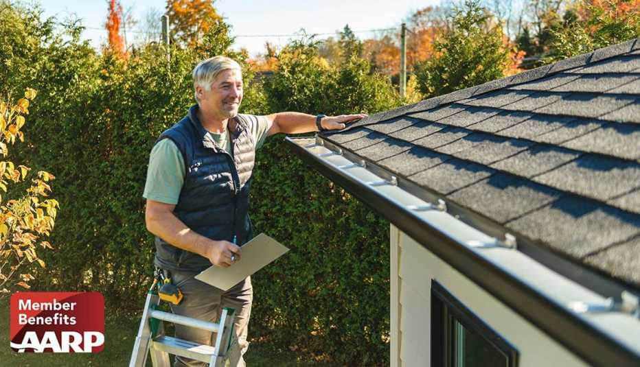 Home inspector standing on a ladder examining a residential roof and gutter system during a home maintenance inspection