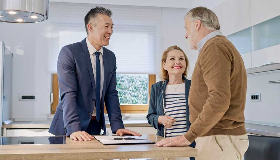 A real estate agent, guides a couple through the final steps of a home-selling process.