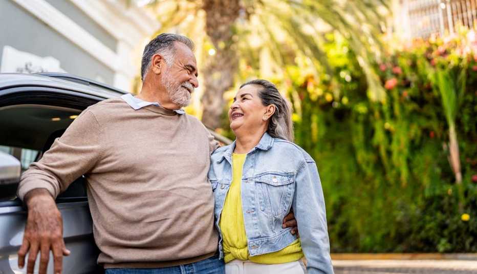 A couple standing next to their car smiling at each other