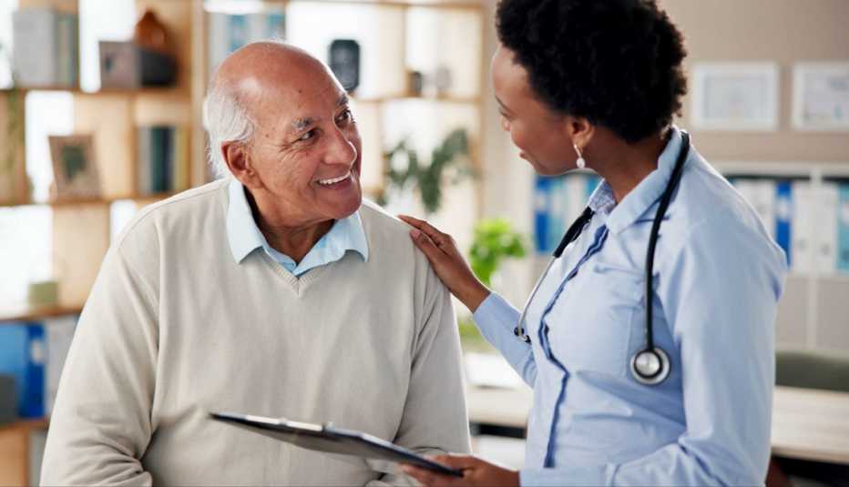 Health care professional with a stethoscope speaking with a patient while holding a clipboard.