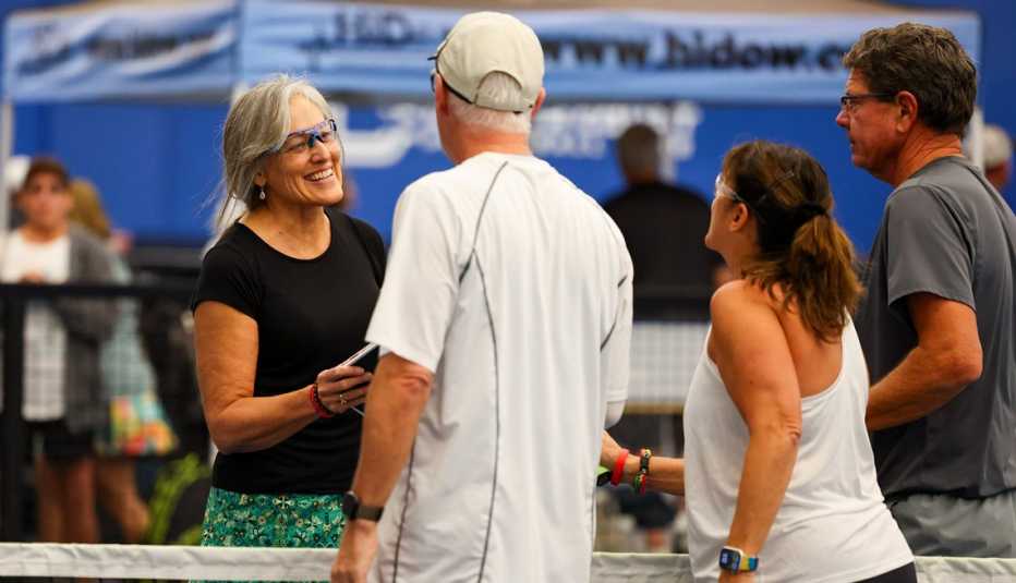 A group of four adults gathers for a conversation beside a net in a large indoor venue
