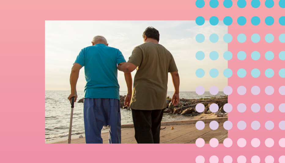 man helping his older father who is leaning on a cane and they are going for a walk along the water