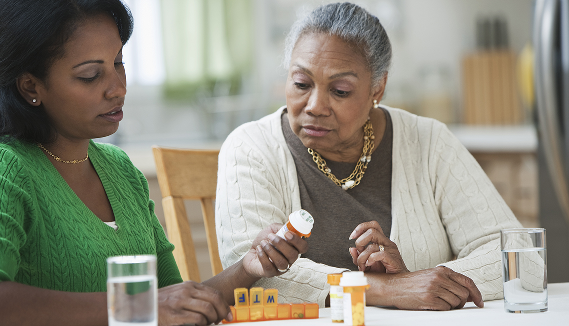A daughter looking through bottles of prescription medication with her mother