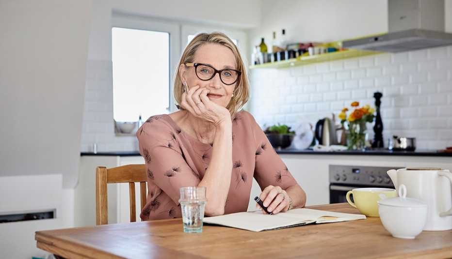 Woman sitting at her kitchen table writing in a journal