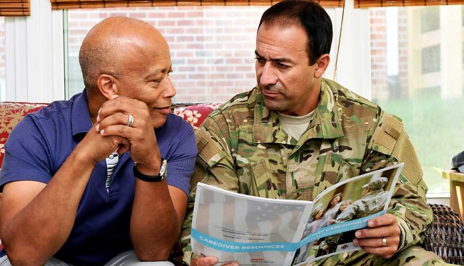 A veteran talks with an active member of the military on a couch about caregiving